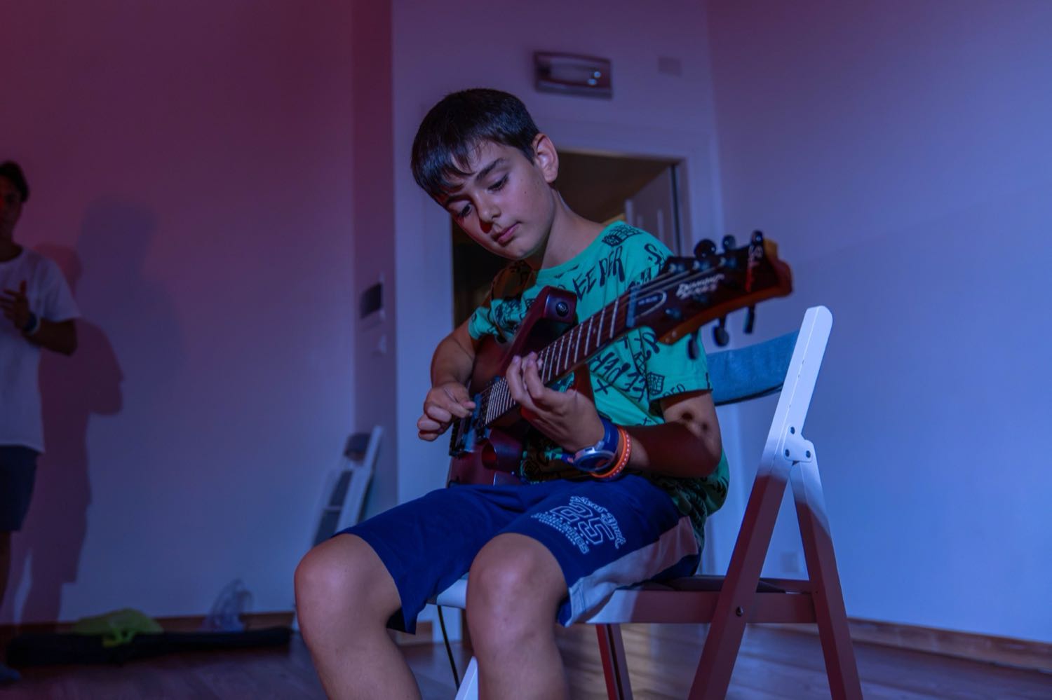 Un chico toca la guitarra, concentrado en las cuerdas