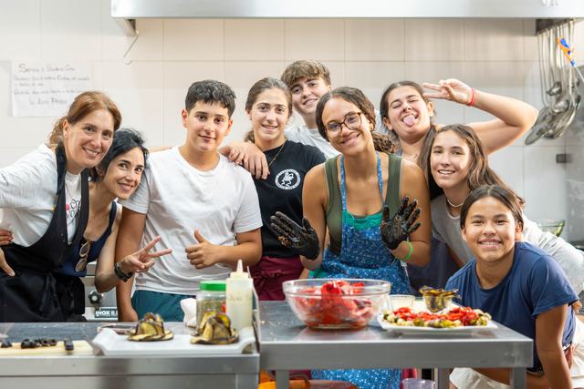 Un grupo cocina junto en la cocina de la finca, con delantales y pulgares arriba